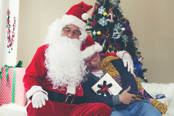 Santa Claus and the young boy with gift boxes. Miracles on Christmas.