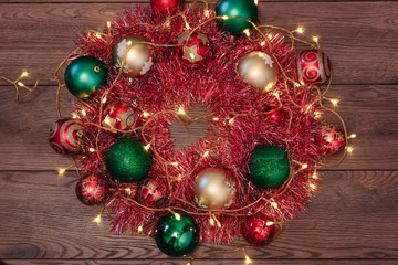 Christmas wreath of red garlands and Christmas toys on the background of a wooden table. Merry Christmas and happy holidays. View from above.