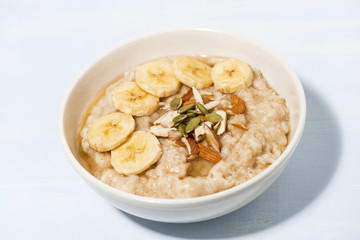 bowl of oatmeal with banana, honey and nuts on table