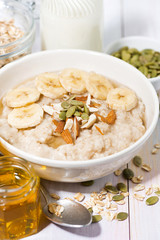 bowl of oatmeal with banana, honey and nuts, vertical closeup