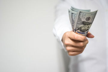 Very happy businessman hand holding and grabbing US dollar (USD) money bills in hand and passing to client in concept of investment, success and profitable business.