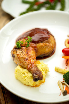 Grilled chicken legs and vegetables in white dish isolated on white plate