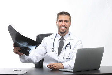 doctor examines an x-ray,sitting behind a Desk