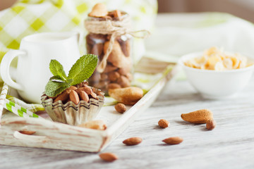 Honey in the bowl, muesli, mint leaves, almonds and jar with milk on the wooden tray