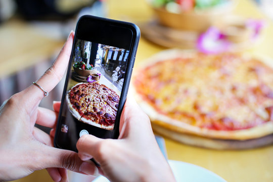 Woman taking a photo of Pizza and Ingredients with smartphone