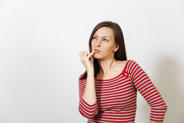 Pretty European young worried and pensive brown-haired woman with healthy clean skin, dressed in casual red and grey clothes lost in thought and conjectures, on a white background. Emotions concept.