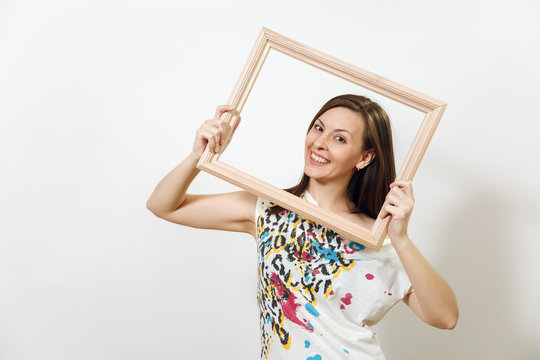 Portrait of a happy smiling brown-haired woman standing and holding empty wooden frame on the white background.