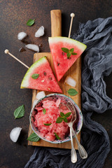 Fresh watermelon cut into pieces and holding granite on  gray stone background. Selective focus.