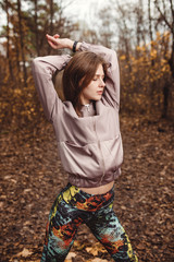 Sporty girl doing gymnastic exercise in autumn forest.