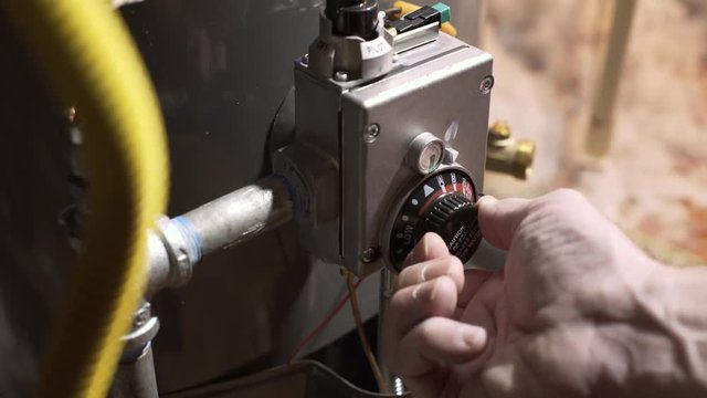 homeowner reducing water heater temperature to conserve energy and save money