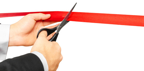 Scissors are cutting red ribbon or tape. Isolated on white background.