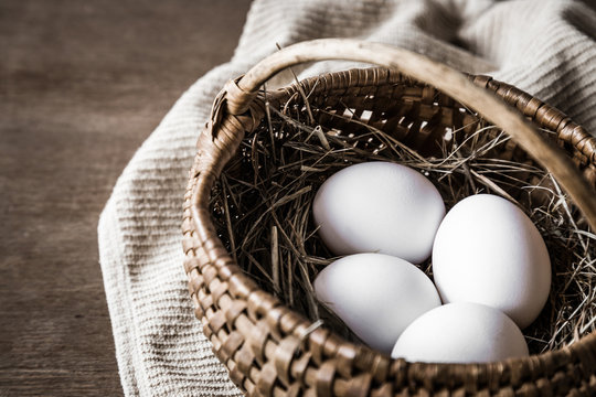 White eggs in the basket in a rustic kitchen. Farm food concept.