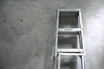 Aluminum step ladder with cement wall background