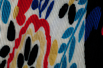Synthetic knitted fabric, white and black background. The flowers are red and blue. A red and blue...