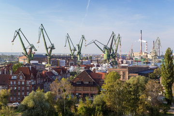 Buildings and shipyard cranes in Gdansk, Poland, viewed from above on a sunny day.