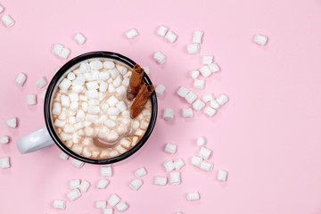 White cup of hot chocolate drink with marshmallows and cinnamon on pink background. Winter time. Christmas holiday concept. Flat lay. Top view.