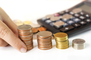 Coins stack with calculator on white table.