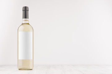 Transparent white wine bottle with blank white label on white wooden board, mock up. Template for advertising, design, branding identity.