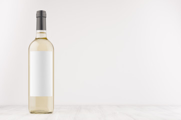 Transparent white wine bottle with blank white label on white wooden board, mock up. Template for...