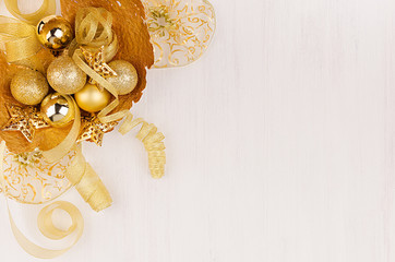 Festive background, gold bowl with stars, balls and ribbons on soft white wooden background, copy space, closeup. Top view.