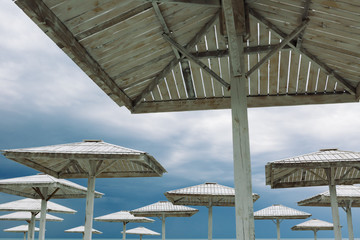 Wooden parasols and empty deckchairs on deserted beach on the off-season cloudy day
