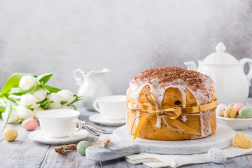 Holidays breakfast concept with copy space. Easter orthodox sweet bread, kulich and colorful quail eggs with white tulips.
