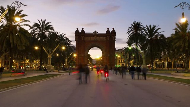Arch of Triumph in Barcelona, Spain at night. Time-lapse of a sunset, motion blurred people, lights and illumination