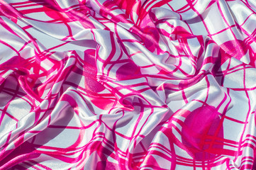 Texture, fabric, background. Texture of a female dress with an abstract red pattern on a white background. Silk fabric geometric shapes