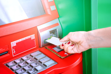 Hand inserting ATM card into bank machine for withdraw money