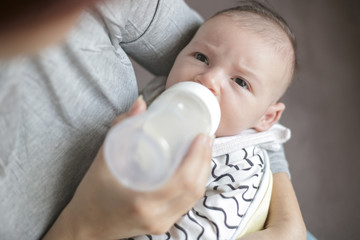 Mother holding and feeding newborn baby from bottle.