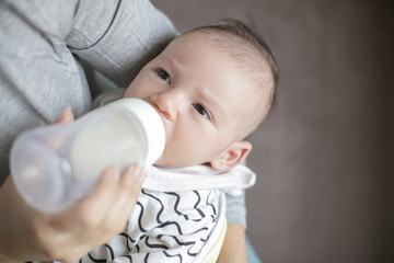 Mother holding and feeding newborn baby from bottle.