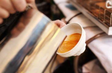 Barista cafe making a cup of coffee latte art in coffee shop.