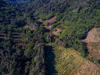 White and red cell phone tower in forest on mountain