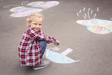 Fototapeta premium Little girl drawing ship with chalk on asphalt