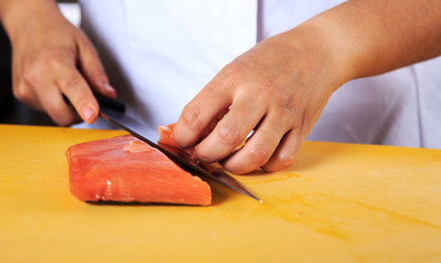Obraz na płótnie Canvas Chef slicing salmon with knife in professional kitchen