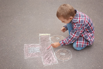 Naklejka premium Little boy drawing car with chalk on asphalt