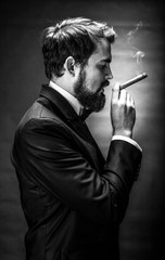 black and white portrait of bearded smoking cigar gentleman in a suit