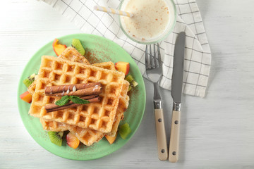 Plate with delicious cinnamon waffles on table