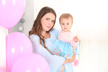Fototapeta na wymiar Young mother holding cute baby on birthday party at home