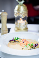Plate of tasty cream of sea food soup with shrimps and mussels on table