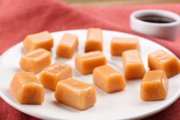 Plate with tasty caramel candies on table, closeup
