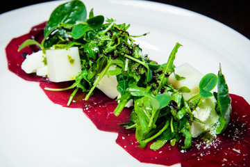 Vegan salad witn cheese beet and lettuce in white plate with black background