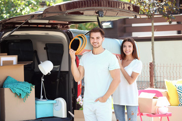 Young couple putting their belongings in car trunk outdoors