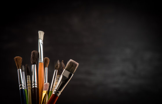Paint brushes in a jar on black background