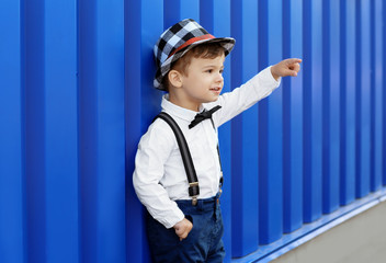 Adorable little boy near blue wall outdoors
