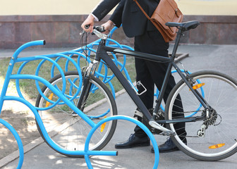 Fototapeta na wymiar Handsome businessman parking his bicycle outdoors