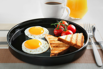 Plate with fried eggs, toasts and cherry tomatoes on table