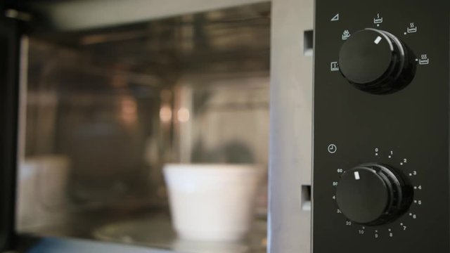 Heating a plastic container with food in a microwave oven. Close-up shot.