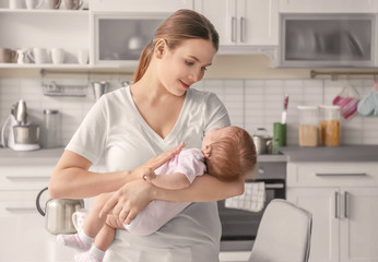 Young mother holding baby in kitchen