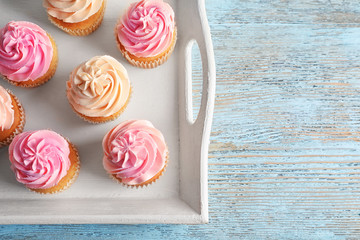Tray with yummy cupcakes on wooden table